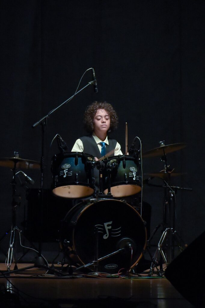 Aurum at the drum kit on a dark stage